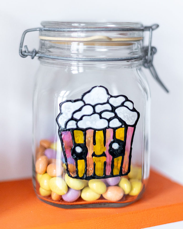 Popcorn figura közelről, cukorkával teli befőttesüvegen